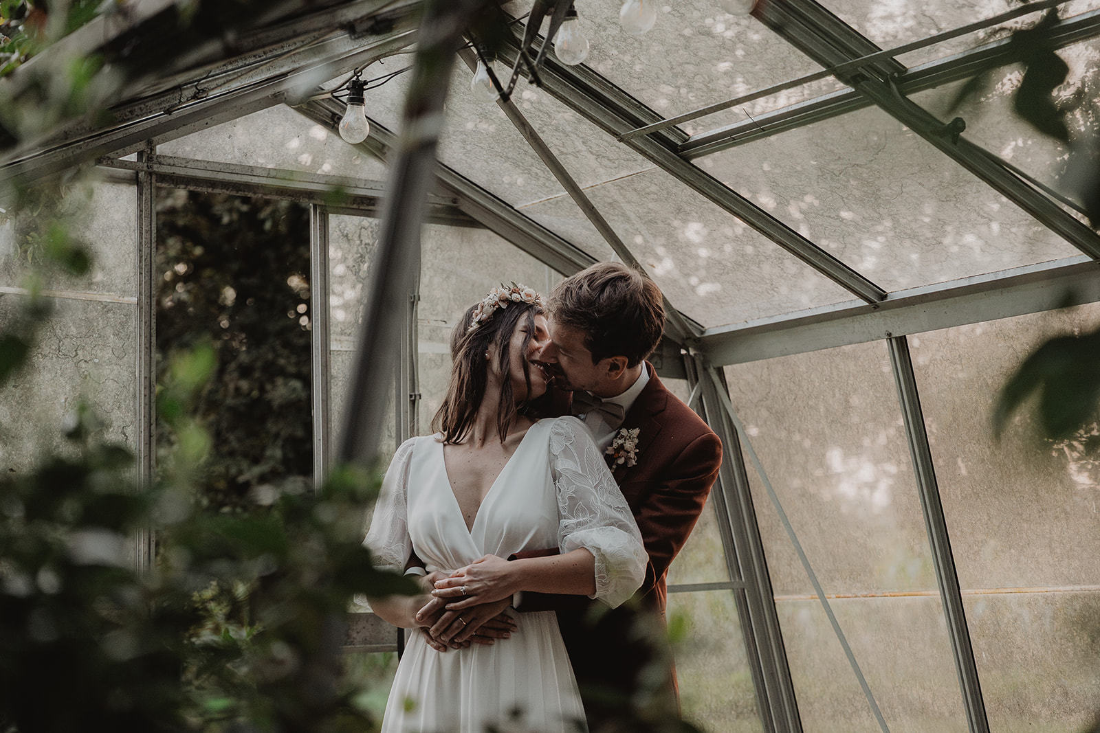 Photo de mariage d'un couple en train de s'enlacer dans une serre