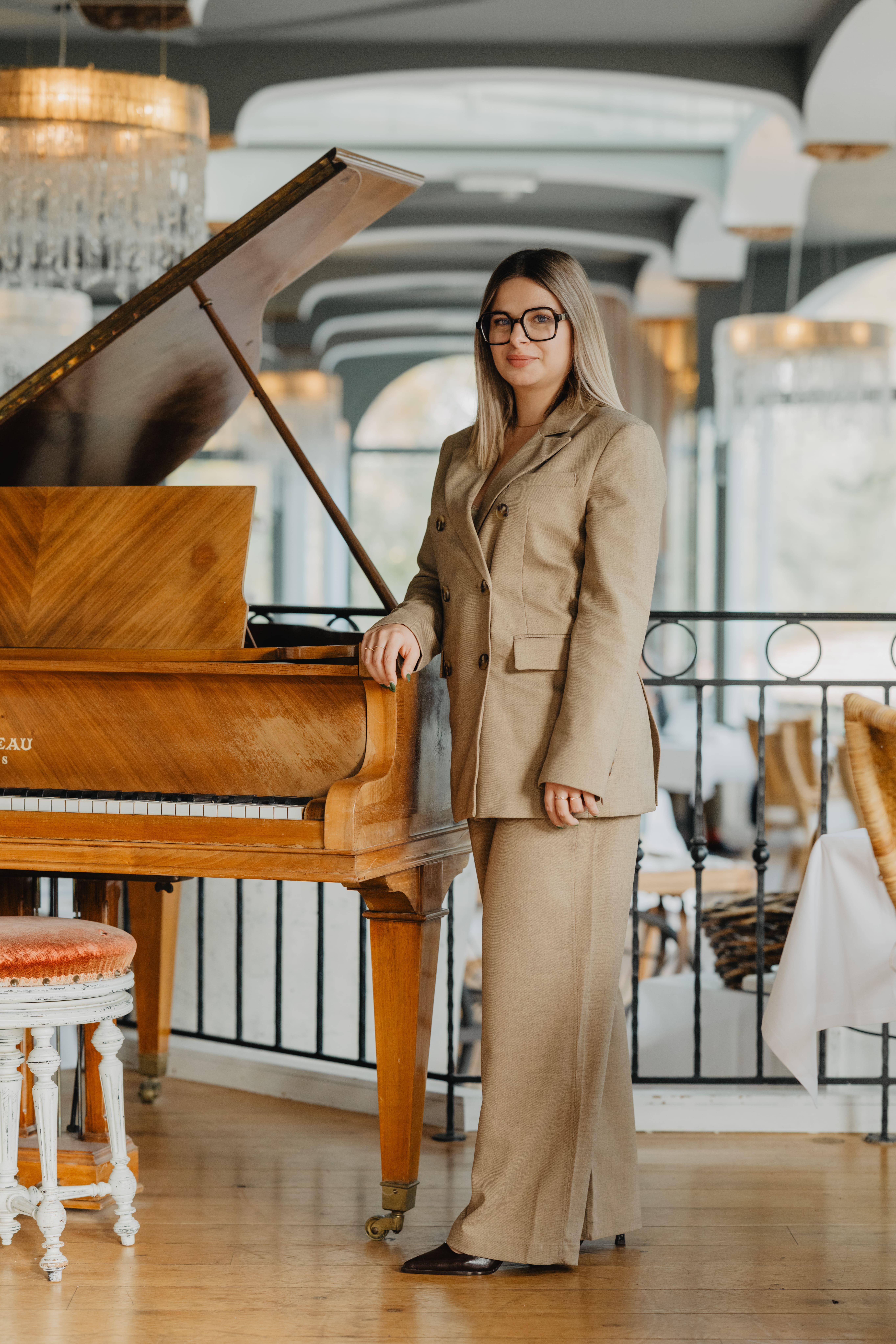 Photo de Orlane, la wedding planner qui couvre la Loire Atlantique et la Vendée. Elle est debout à côté d'un piano dans un très beau lieu.