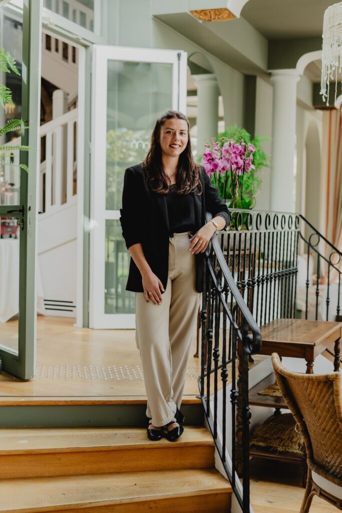 Photo de Mathilde, la wedding planner qui couvre la région bordelaise. Elle est debout à côté d'une rambarde d'escalier dans un très beau lieu.